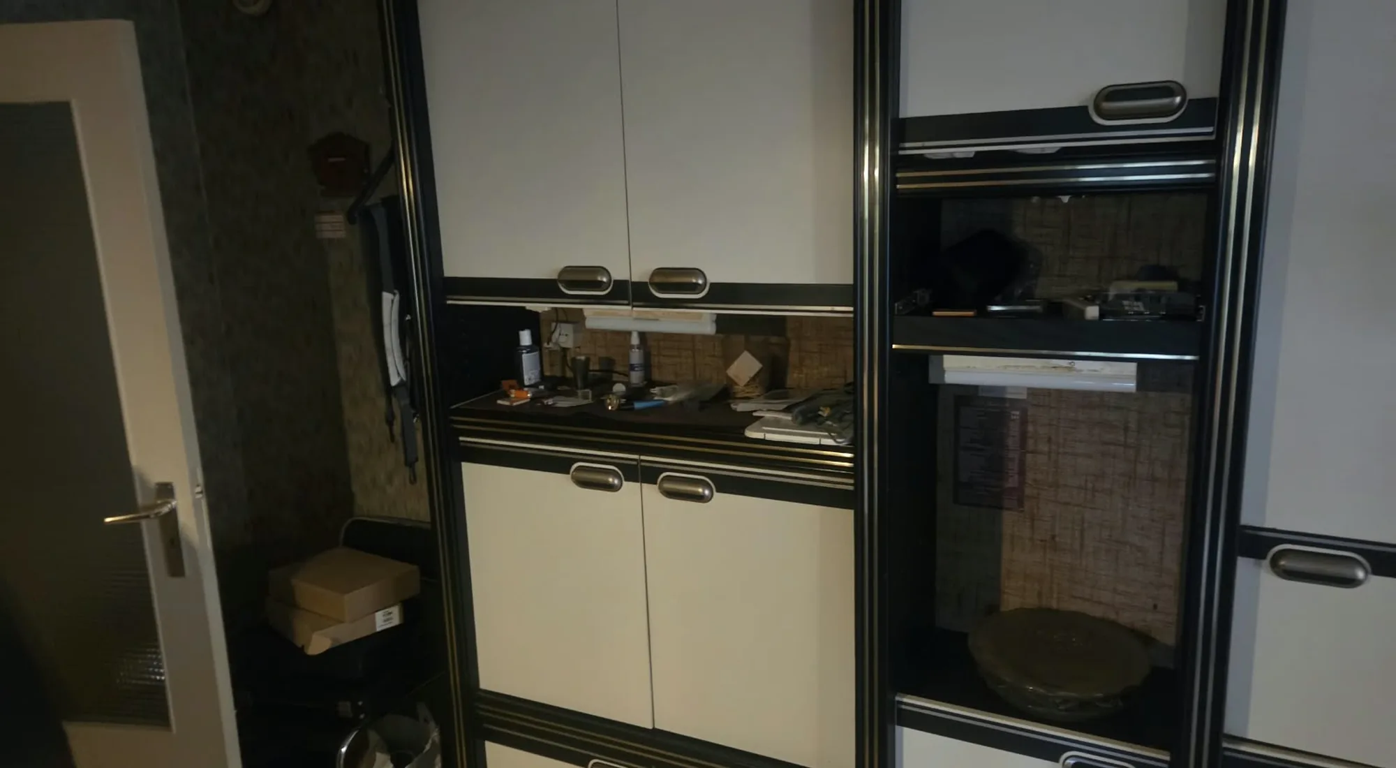 Appartement leegmaken: zwart-witte kastenwand met kleine spullen op het werkblad