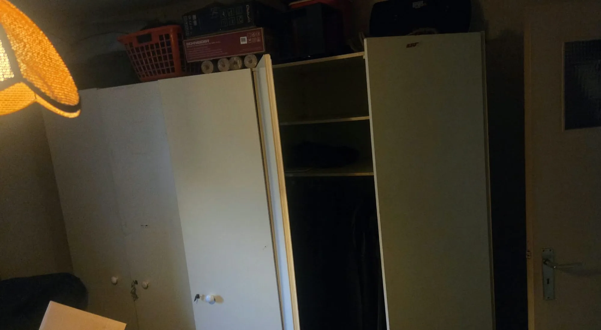 Appartement leegmaken: witte kleerkast met dozen en manden erop